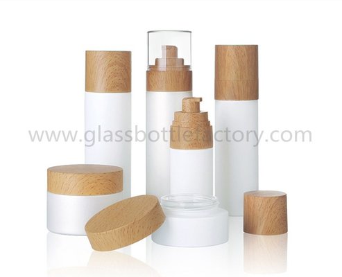 China New Items Cylinder Glass Lotion Bottles With Pumps For Skincare and Glass Cream Jars With Wood Caps supplier